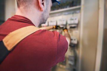 Electrician working on a modern electricity power meter station in a building.