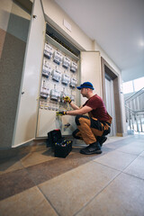 Electrician working on a modern electricity power meter station in a building.