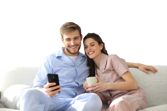 Young couple watching online content in a smart phone sitting on a sofa at home on a transparent background - Powered by Adobe