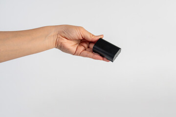 Black DSLR camera battery and hand on white background