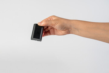 Black DSLR camera battery and hand on white background