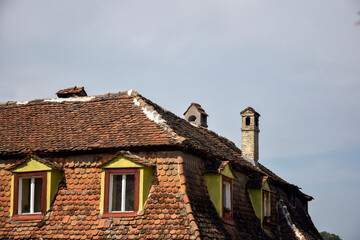 Attic roof of house made of red tiles with chimney and windows. Copy space. Selective focus.