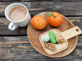 Breakfast with oranges, Asian market snacks and a glass of tea is served on a wooden table. High angle view of breakfast on table.