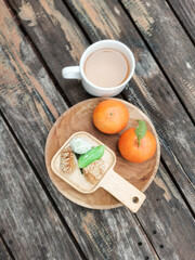 Coffee, mandarins, and cookies on a wooden tray.  High angle view of breakfast on table