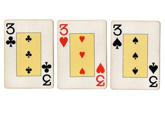 Vintage playing cards showing three of the same value on a white background.