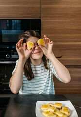 Young girl having fun in the kitchen, holding two heart shaped cookies over her eyes, expressing playfulness and enjoyment. Happy little girl looking at camera while covering her eyes with biscuits.