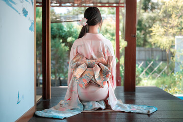 Elegant Woman in Traditional Kimono Sitting Gracefully Outdoors