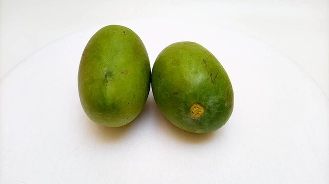 Fresh green mango fruits rotating on white background, tropical fruit, unripe mangoes for pickle