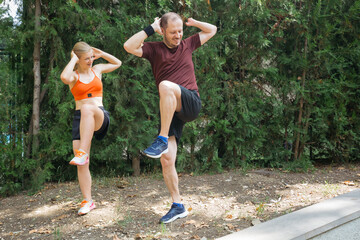 Man and woman doing high knee exercises outdoors.  Active couple working out together in a park, improving fitness and health.  Great for fitness, wellness, and healthy lifestyle concepts.