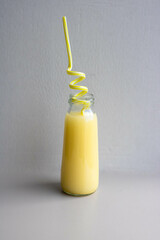 A bottle of yellow drink with a yellow straw. Cocktail Straw Day