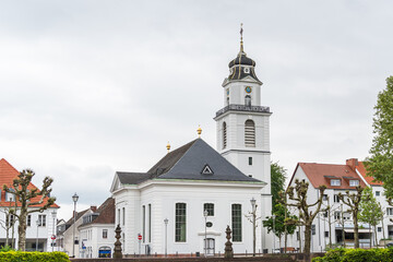 A white Friedenskirche church with a clock tower and a steeple in Saarbrucken Germany