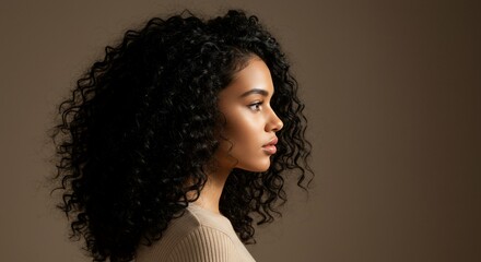 Profile of a young woman with curly hair against a neutral background