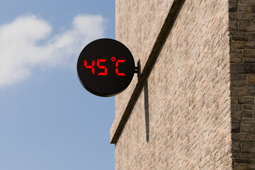 Street digital thermometer displaying a temperature of 45 degrees Celsius with blue sunny background. 