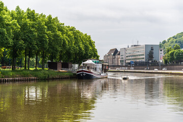 A boat is traveling down a Saar river near a Saarbrucken city in Germany