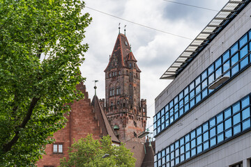 A tall building with a clock tower and a tree in front of it in Saarbrucken Germany
