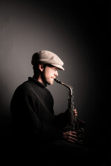 Naklejka premium solitary jazz musician playing saxophone in dimly lit room soft glow of single light illuminating their face