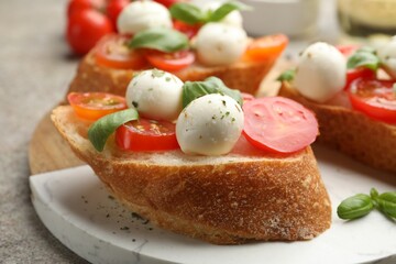 Tasty sandwiches with mozzarella cheese balls, tomato and basil on grey table, closeup