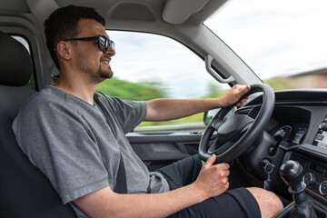 Happy man driving car. Smiling driver on the road. Confident travel in motion.