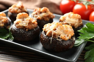 Delicious stuffed mushrooms with parsley and tomatoes on table, closeup