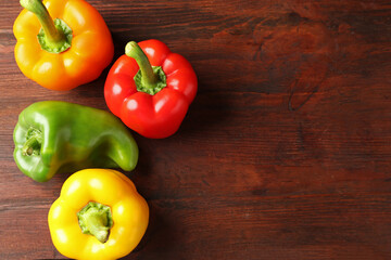 Ripe colorful bell peppers on wooden table, flat lay. Space for text