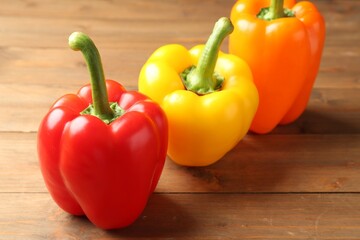 Ripe colorful bell peppers on wooden table, closeup