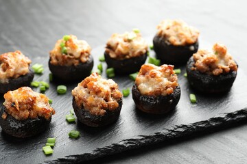Tasty stuffed mushrooms served on black table, closeup