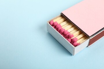 Matches in box on light blue background, closeup. Space for text