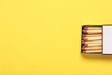 Matches in box on yellow background, top view. Space for text