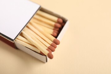 Matches in box on beige background, closeup. Space for text