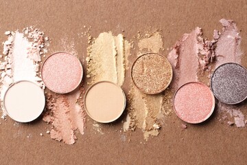 Beautiful eyeshadow refill pans on brown background, flat lay