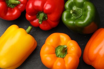 Fresh colorful bell peppers on dark gray table, flat lay