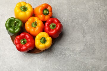 Fresh colorful bell peppers on gray textured table, top view. Space for text