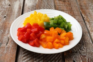Cut colorful bell peppers on wooden table, closeup