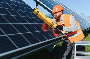 Engineer installing solar panels using level tool in solar power station