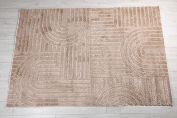 Stylish rug with pattern on light wooden floor, top view