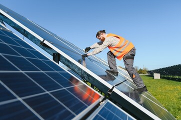 Technician installing solar panels in a solar farm for green energy production