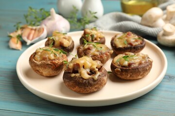 Delicious stuffed mushrooms with melted cheese and thyme on light blue wooden table, closeup