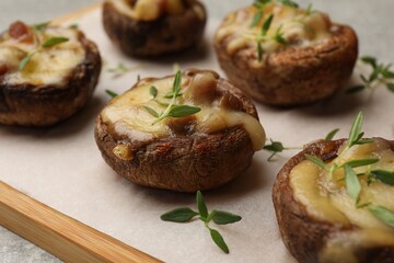 Delicious stuffed mushrooms with melted cheese and thyme on grey table, closeup