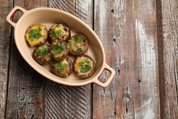 Delicious stuffed mushrooms with melted cheese and parsley in baking dish on color wooden table, top view. Space for text