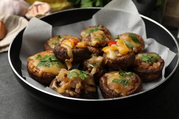 Tasty stuffed mushrooms in frying pan on black table, closeup