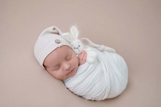 Peaceful newborn baby wrapped in white blanket