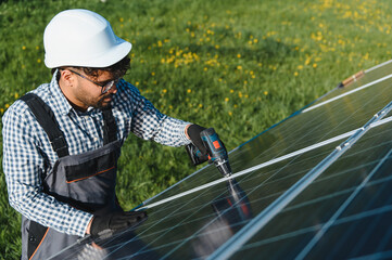 Technician installing solar panel in green field using screwdriver