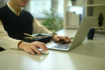 Close up of man using a laptop and mouse while having lunch at a desk