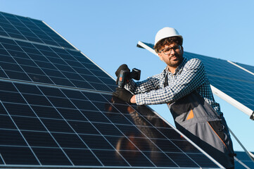 Engineer installing solar panel using electric drill on sunny day