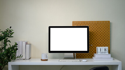 Contemporary workstation with blank screen monitor, plant, pegboard wall, and calendar