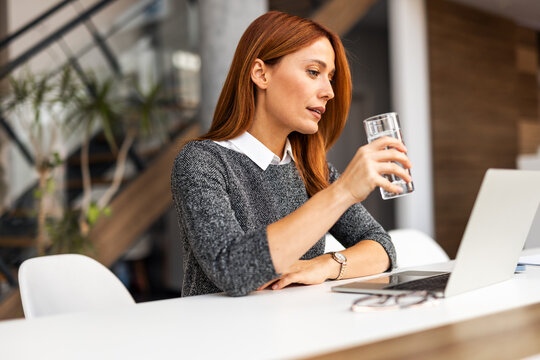 Professional Woman Working at Desk and Drinking Water in Office