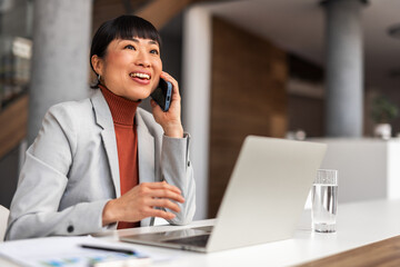 Smiling Professional Businesswoman Talking on Smartphone in Modern Office