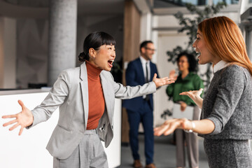 Two Excited Female Colleagues Joyfully Greeting in a Modern Office Setting