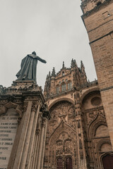 Statue of Fray Luis de LeÃ³n standing before the ornate facade of the New Cathedral of Salamanca,...