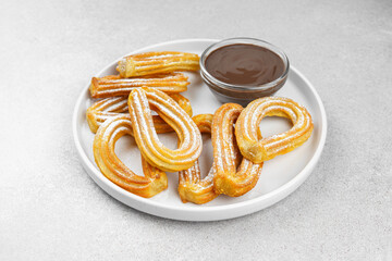 Traditional spanish dessert churros, fried dough pastry dusted with powdered sugar and chocolate sause on white background. Street food, sweet snack, homemade dessert. Top view, copy space